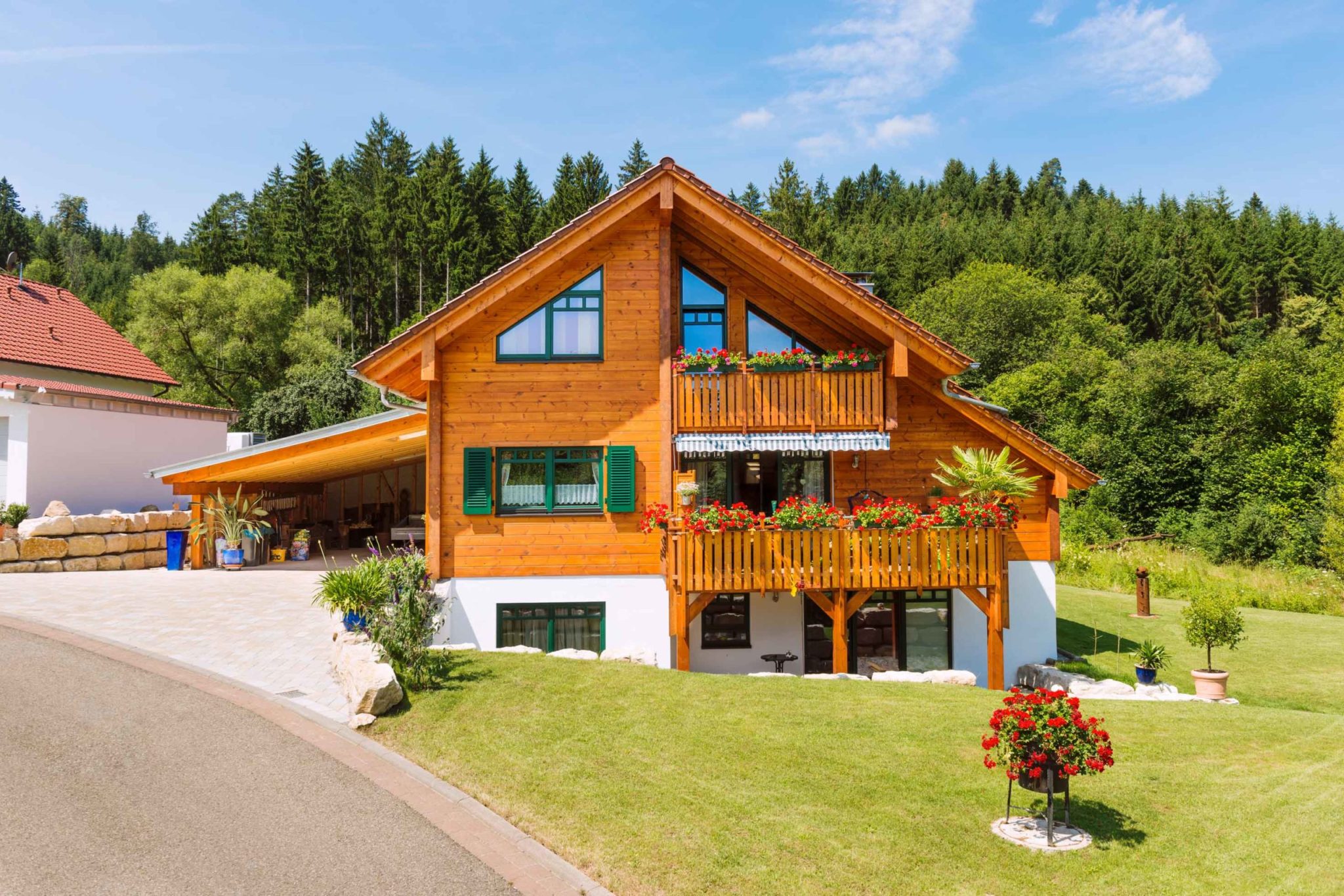 Holzhaus im Landhausstil von Fullwood mit hellbrauner Kiefernfassade, tannengrünen Fensterläden und umlaufenden Holzbalkonen mit Blick in die Natur.